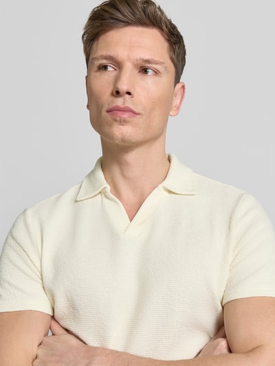 Męski model nosi Regular Fit Poloshirt aus Baumwoll-Mix od MCNEAL, bawełna z elastanem, waffle-piqué, V-dekolt, krótki rękaw, neutralny kolor, tekstura o wyraźnej strukturze, ujęcie: zbliżenie górnej części ciała.