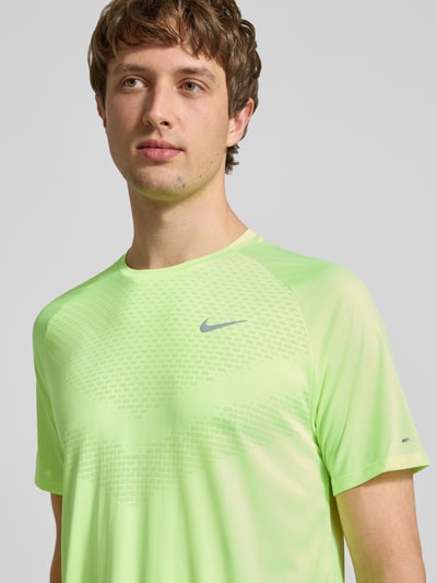Männermodel trägt Herren Funktionsshirt mit Logo und Rundhalsausschnitt Modell 'Stride' von NIKE TRAINING in Neongelb, Nahaufnahme Oberkörper, Regular-Fit, Rückenlänge bei Größe M: 73 cm.