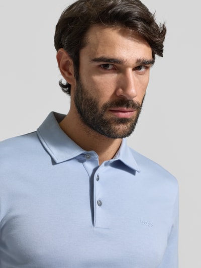 Männermodel trägt Regular Fit Poloshirt aus reiner Baumwolle Modell 'PALOSH' von BOSS, Optik: Unifarben, Label-Print, Nahaufnahme Oberkörper.