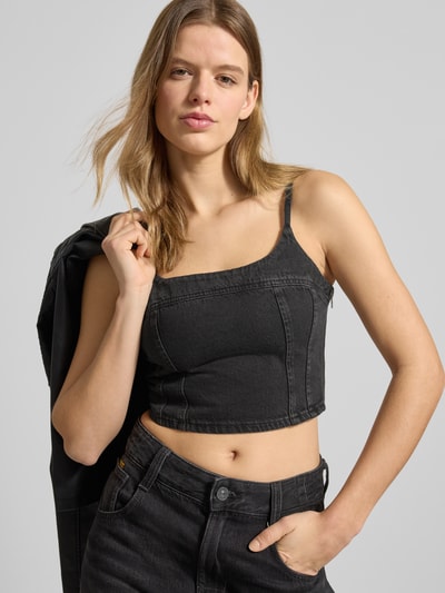 Frauenmodel trägt Slim Fit Crop Top aus reiner Baumwolle Modell 'JADINE' von Levi’s®, schwarzer Denim, Karree-Ausschnitt, Nahaufnahme Oberkörper.