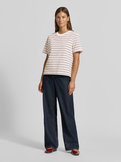 Frauenmodel trägt Boxy Fit T-Shirt aus reiner Baumwolle Modell 'ESSENTIAL' von Selected in Weiß mit braunen Streifen, kombiniert mit dunkelblauer Jeans, Damen T-Shirt von Selected, Ganzkörperansicht von vorne.