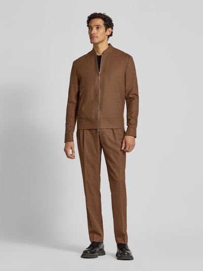 Männermodel trägt Slim Fit Hose in Flanell-Optik von MCNEAL in Braun, elastischer Material-Mix, Bügelfalten, Ganzkörperansicht von vorne.