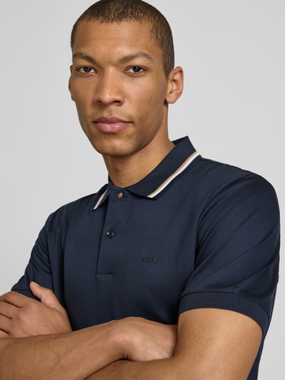 Männermodel trägt Slim Fit Poloshirt aus reiner Baumwolle Modell 'PENROSE' von BOSS in Unifarbe, Nahaufnahme Oberkörper.