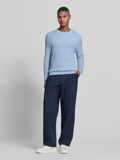 Mannenmodel draagt Regular Fit Gebreide pullover uit puur katoen van Tommy Hilfiger met effen kleuren, gebreide look, longmouwen, ronde hals, logodetail, rompzoom, frontaal volledig lichaamsaanzicht.