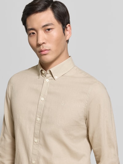Męski model nosi koszulę casualową Slim Fit Freizeithemd mit Button-Down-Kragen Modell 'Anton' od Casual Friday, mieszanka jedwabiu i bawełny, kolor beżowy, długość tyłu w rozmiarze M: 78 cm, szerokość ramion w rozmiarze M: 46 cm, długość rękawów w rozmiarze M: 66 cm, z przodu ujęcie zbliżenie na górną część ciała.