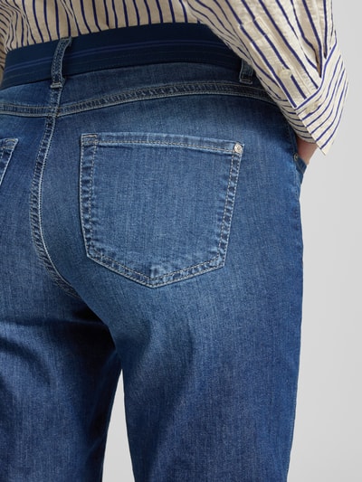 Männermodel trägt Jeansshorts mit Umschlag und elastischem Bund von Angels, bawełna z elastanem, krój regular fit, szerokość w rozmiarze 36: 39 cm, długość wewnętrzna nogawki w rozmiarze 36: 30 cm, dżins w kolorze niebieskim, widoczna tylna kieszeń, detal z tyłu, zbliżenie tylnej części.