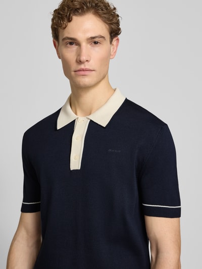 Männermodel trägt Slim Fit Poloshirt mit Logo-Stitching von Gant in Dunkelblau, Polokragen, Baumwoll-Modal-Mix, Nahaufnahme Oberkörper.