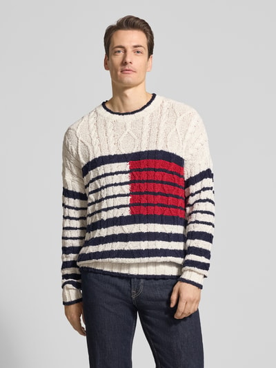 Männermodel trägt Relaxed Fit Strickpullover aus reiner Baumwolle von Tommy Hilfiger, Optik: unifarben, Strickoptik, Logo-Detail, Rundhals, Langarm, gerippte Abschlüsse, Material: reine Baumwolle, Ganzkörperansicht von vorne.