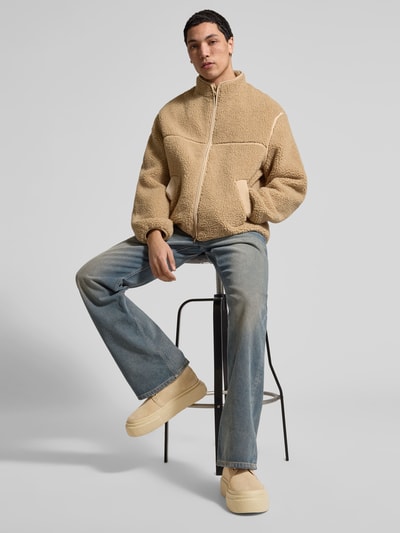 Männermodel trägt Sneaker mit Schnürverschluss von MM6 Maison Margiela, beiger Farbton, Plateau, strukturierte Sohle, Ganzkörperansicht von vorne.