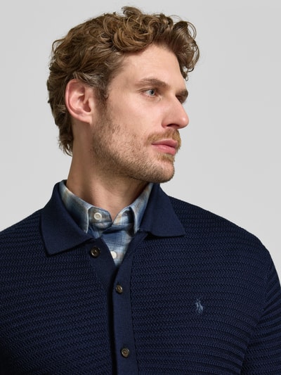 Mężczyznamodel nosi Regular Fit Strickjacke aus reiner Wolle von Polo Ralph Lauren, granatowy kolor, tekstura dzianinowa, Nahaufnahme górnej części ciała.
