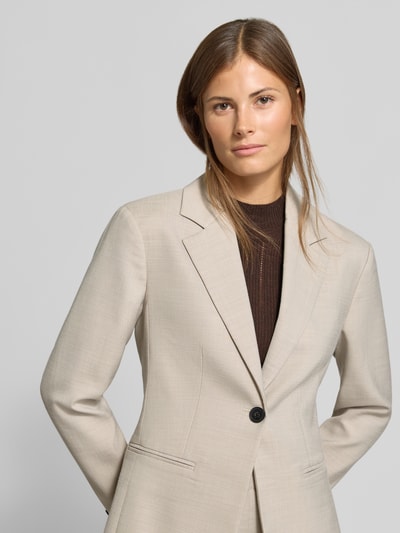 Frauenmodel trägt Slim Fit Anzugblazer mit Viskose-Anteil von MYON, beigefarbener Stoff, Knopfverschluss, seitliche Paspeltaschen, Nahaufnahme Oberkörper.