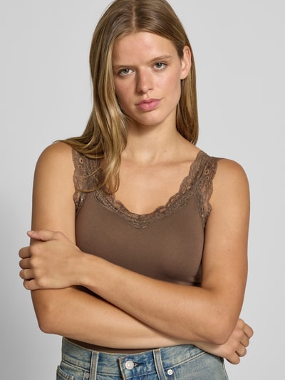 Frauenmodel trägt Slim Fit Tanktop aus Viskose-Mix Modell 'BARBERA' von PIECES in Braun mit Spitzendetails, Nahaufnahme Oberkörper.