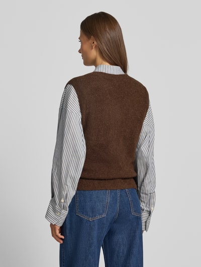 Frauenmodel trägt Strickweste mit Rundhalsausschnitt Modell 'Bondie Hope' von MSCH Copenhagen, Mix mit Woll-Anteil, Regular Fit, Rückenlänge 58 cm, braune Farbe, kombiniert mit gestreifter Bluse und blauer Jeans, Ganzkörperansicht Rückansicht.