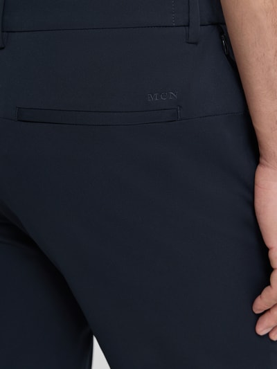 Männermodel trägt Tapered Fit Hose mit Gesäßtaschen von MCNEAL in Dunkelblau, glatte Oberfläche, Nahaufnahme Gesäßbereich. Bundweite 45 cm, Innenbeinlänge 80 cm, Eingrifftaschen, Knopf- und Reißverschluss, Größe M.