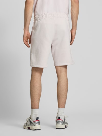 Männermodel trägt Regular Fit Shorts mit Logo-Stitching von Pegador aus Baumwoll-Mix in Hellrosa, elastischer Bund, Ganzkörperansicht Rückansicht.