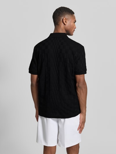 Männermodel trägt Poloshirt aus reiner Baumwolle Modell 'JACQ' von BOSS Green x Porsche, schwarz, Strukturmuster, Ganzkörperansicht Rückansicht.