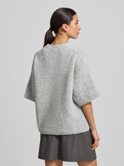 Modelka nosi Strickpullover mit gerippten Abschlüssen Modell 'ZOLLY' od American Vintage, jasnoszary, luźny krój, melanżowa tekstura, sweter z okrągłym dekoltem i półrękawami, mieszanka wełny z dodatkiem alpaki, długość tyłu 60 cm w rozm. XS/S, zakończenia ze ściągaczem, widok całej sylwetki od tyłu.