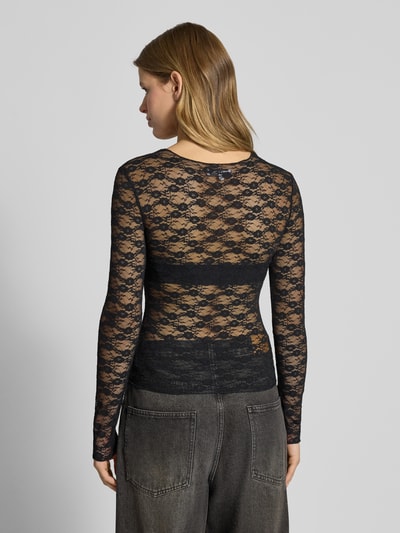 Frauenmodel trägt schwarzes Langarmshirt aus Spitze von Review mit figurbetonter Passform und Rundhalsausschnitt, Ganzkörperansicht Rückansicht.