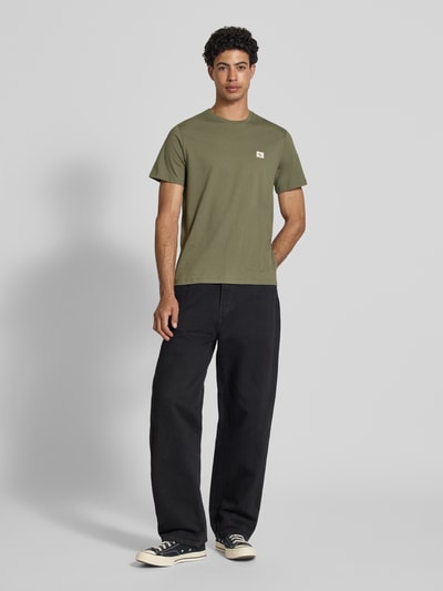 Mannelijk model draagt Regular Fit T-Shirt uit zuiver katoen van Calvin Klein Jeans in effen groen met label patch, ronde hals, korte mouw, regular fit, materiaal katoen, volledige lichaamsweergave van voren.