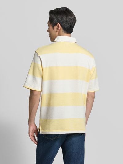 Männermodel trägt Relaxed Fit Poloshirt im Allover-Look von MCNEAL in Gelb und Weiß aus Baumwoll-Mix mit Knopfleiste, Rückenlänge 70 cm, Ganzkörperansicht Rückansicht.
