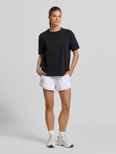 Frauenmodel trägt Regular Fit Sweatshorts mit Logo-Applikation von Lacoste, Optik: Unifarben, Bundabschluss: Elastisch, seitliche Eingrifftaschen, Materialverarbeitung: Sweat, Ganzkörperansicht von vorne.