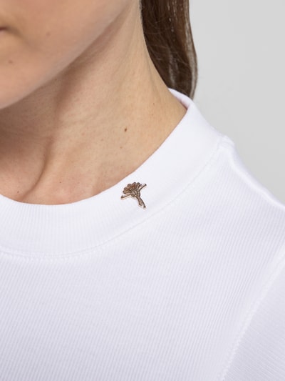 Mädchen trägt Slim Fit Top mit Logo-Detail Modell 'Tonda' von JOOP!, biały, okrągły dekolt, faktura prążkowana, Nahaufnahme Oberkörper, długość tyłu 62 cm w rozmiarze 36