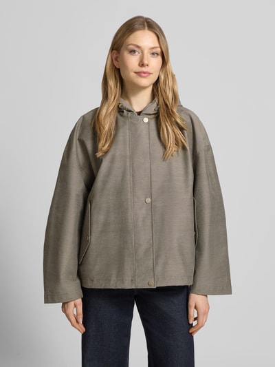 Frauenmodel trägt Regular Fit Jacke mit Kapuze Modell 'Elle' von G-LAB in Khaki mit Druckknopfverschluss, Eingrifftaschen, Tunnelzug, Ganzkörperansicht von vorne. Rückenlänge 64 cm, Schulterbreite 56 cm, Brustweite 56 cm, Ärmellänge 51 cm bei Größe S.