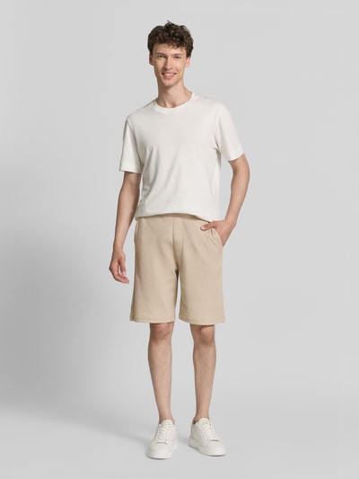 Männermodel trägt Relaxed Fit Sweatshorts aus Baumwoll-Mix von s.Oliver RED LABEL, beige, unifarben, Piqué-Struktur, Ganzkörperansicht von vorne.