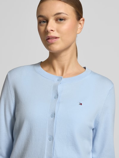 Frauenmodel trägt Regular Fit Strickjacke aus Baumwoll-Mix von Tommy Hilfiger, hellblau, Rundhals, Knopfleiste, Logo-Stitching, Nahaufnahme Oberkörper.