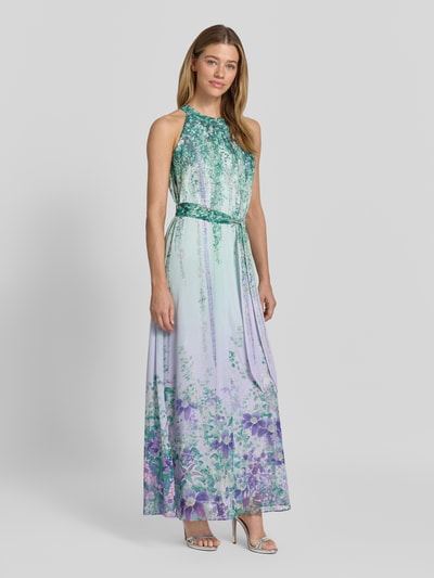 Frauenmodel trägt Maxikleid mit Bindegürtel von Marc Cain in A-Linie, Neckholder, Allover-Look, grün-lila, Ganzkörperansicht von vorne.