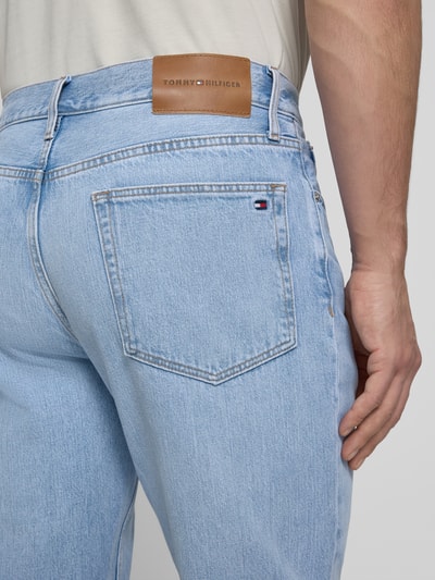 Männermodel trägt Tapered-Fit Herren Jeans aus reiner Baumwolle Modell 'HARLEM' von Tommy Hilfiger in Denim-Optik, Nahaufnahme Rückansicht.