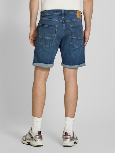 Männermodel trägt Jeansshorts mit Umschlag Modell 'RICK' von Jack & Jones aus Baumwoll-Mix mit Stretch-Anteil, Regular-Fit, Ganzkörperansicht Rückansicht.
