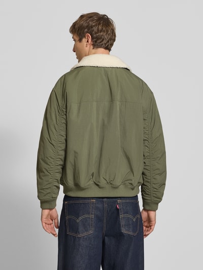 Männermodel trägt Regular Fit Bomberjacke mit abnehmbarem Teddy-Kragen von Tommy Jeans, grün, weiche Textur, Ganzkörperansicht Rückansicht, Herren Bomberjacke / Blouson.