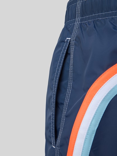Produktfoto, Badehose mit elastischem Bund Modell 'UNI SHORTS NEON' von Sundek, blaue Farbe mit weißen Nähten und bunten Streifen, strukturierte Textur, Regular Fit, Nahaufnahme seitlich