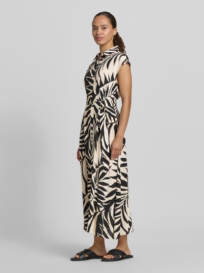 Frauenmodel trägt Hemdblusenkleid aus Viskose mit Bindegürtel Modell 'APPLE' von Mango im taillierten Schnitt mit Kappärmeln und Knopfleiste, Midikleid in Schwarz-Beige mit Blätter-Muster, glatte Textur, Ganzkörperansicht von vorne.
