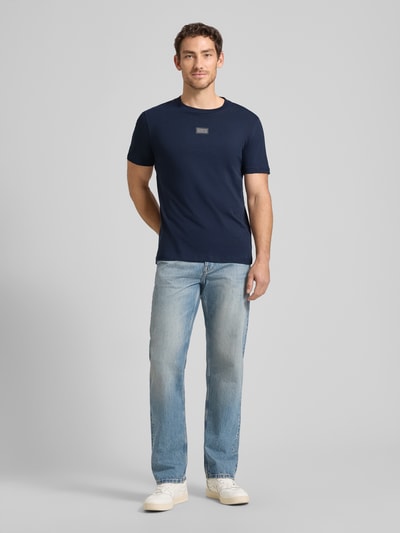 Männermodel trägt Regular Fit T-Shirt aus reiner Baumwolle von Tom Tailor Denim in Dunkelblau, dezenter Label-Schriftzug, Rundhalsausschnitt, kurzarm, unifarbene Optik, Ganzkörperansicht von vorne.