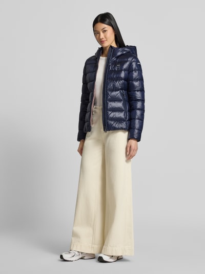 Frauenmodel trägt dunkelblaue Jacke in Stepp-Optik Modell 'CAROLL' von Blauer USA, glänzende Oberfläche, Ganzkörperansicht von vorne.