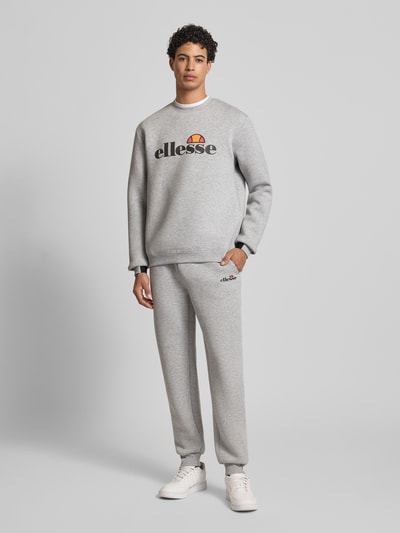 Mężczyzna nosi Sweatshirt mit Label-Print Modell 'CORVARO' od Ellesse, szary materiał-mix z wiskozą, luźny krój, ściągacze, przód, widok całej sylwetki