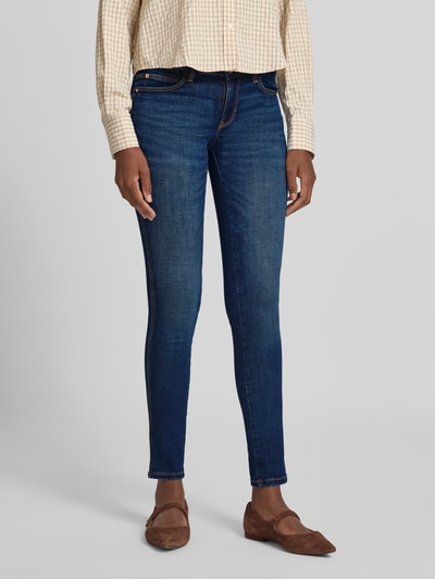 Vrouwenmodel draagt Slim Fit Jeans uit katoenmix Model 'Curve' van GUESS, blauw, 5-pocketmodel, knoop- en ritssluiting, voorkant, binnenbeenlengte maat 27/30: 78 cm, bandwijdte: 37 cm, detailrijke structuur. Ganzkörperaanzicht van voren.