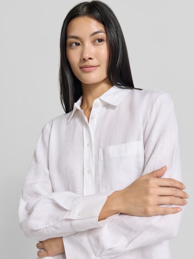 Frauenmodel trägt Leinenbluse mit Brusttasche Modell 'LINO' von MANGO in Weiß, Hemdblusenkragen, Knopfleiste, Nahaufnahme Oberkörper.