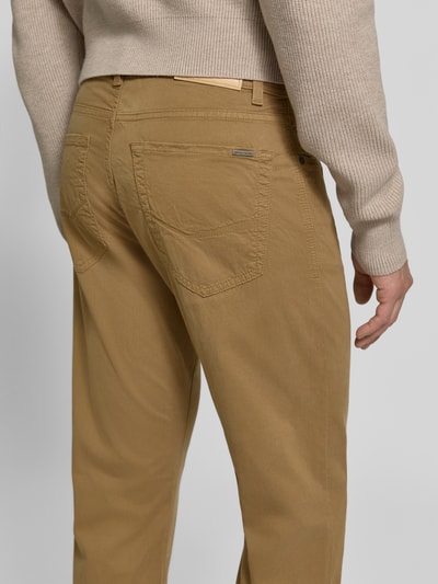 Männermodel trägt Straight Fit Jeans aus elastischem Baumwoll-Mix Modell 'Lyon' von Pierre Cardin w kolorze camel, 5 kieszeni, szlufki na pasek, zapięcie na guzik i zamek błyskawiczny, szerokość w rozmiarze 32/34: 41 cm, długość wewnętrzna nogawki w rozmiarze 32/34: 86 cm, mieszanka bawełny i elastanu, widoczna struktura materiału, detaliczne przeszycia, tylne kieszenie, ujęcie: widok z tyłu, detailaufnahme.