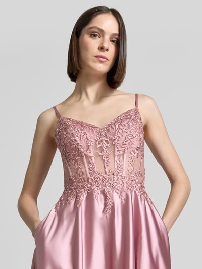 Kobiece modelka nosi sukienka gorsetowa z satyny od Luxuar, taliowany krój, hafty, obszycie ozdobnymi kamieniami, długość tyłu 131 cm w rozmiarze 36, szerokość klatki piersiowej 32 cm w rozmiarze 36, z wiązaniem z tyłu, długa sukienka, kolor różowy, struktura gładka, zbliżenie górnej części ciała