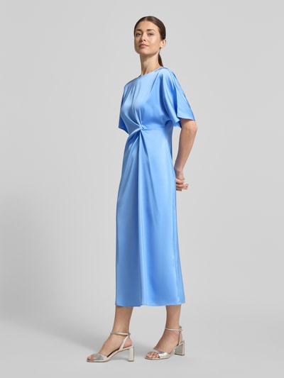 Vrouwenmodel draagt Midikleid met Knotendetail Modell 'Dela' van JOOP! in lichtblauw satijn, recht fit, ronde hals, zijaanzicht, geheellichaamsaanzicht van voren.