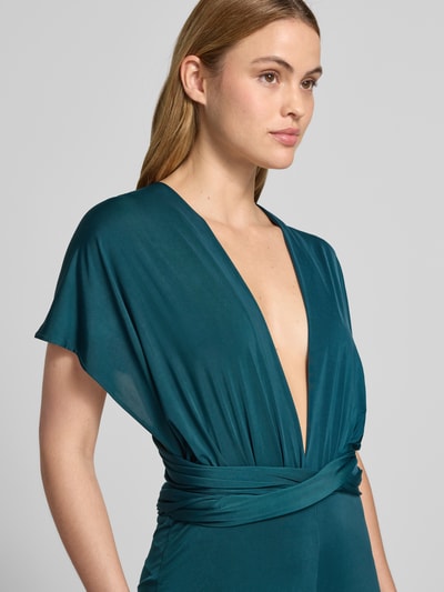 Frauenmodel trägt Jumpsuit mit rückseitig gekreuzten Trägern von Rose Avenue in Petrol, tiefer V-Ausschnitt, glatte Textur, Nahaufnahme Oberkörper. Regular Fit, Rücklänge 120 cm, Brustweite 50 cm, Innenbeinlänge 92 cm, mit Raffungen.