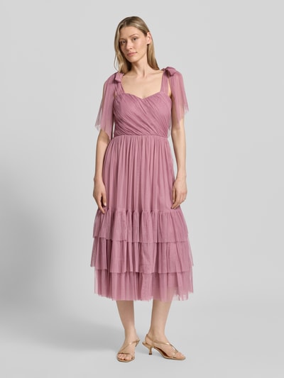 Frauenmodel trägt knielanges Cocktailkleid im Stufen-Look von LACE & BEADS aus Mesh in A-Linie mit Drapierungen, Ganzkörperansicht von vorne. Rückenlänge bei Größe S: 104 cm, Brustweite bei Größe S: 40 cm.