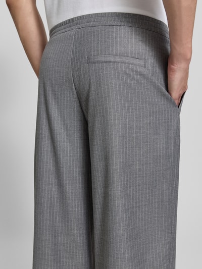 Männermodel trägt graue Herren Jog Pants mit feinen weißen Streifen, Modell 'YROWAY' von American Vintage, Material-Mix mit Viskose-Anteil, Straight Fit, elastischer Bund, Gesäßleistentasche, Bundweite 42 cm, Innenbeinlänge 73 cm, Nahaufnahme Rückansicht.