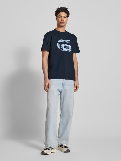 Männermodel trägt Regular Fit T-Shirt mit Logo-Print Modell 'icon' von G-Star Raw aus reiner Baumwolle, Rundhalsausschnitt, dunkelblau, Ganzkörperansicht von vorne.