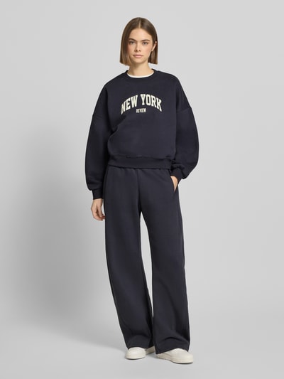 Vrouwenmodel draagt Sweatshirt met Label-Print en Rundhalsausschnitt van Review in donkerblauw Katoenmix Relaxed fit Ganzkörperansicht von vorne