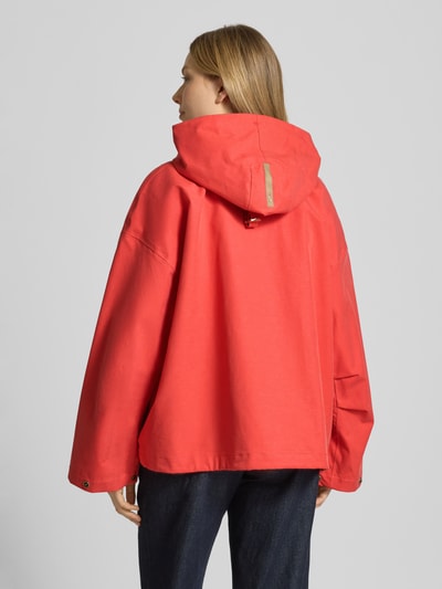 Frauenmodel trägt Jacke mit Kapuze und versiegelten Nähten Modell 'ELLE' von G-LAB im Lyocell-Mix mit Leinen-Anteil, Gerader-Schnitt, Wasserdicht, Winddicht und Atmungsaktiv, Farbe Rot; Ganzkörperansicht Rückansicht.