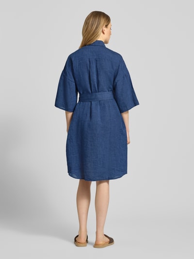 Vrouwenmodel draagt Leinenkleid aus reinen Leinen Modell 'Derby' von 0039 Italy in donkerblauw, getailleerde pasvorm, halflange mouwen, platte kraag, doorlopende knoopsluiting, semi-transparant design, afneembare stoffen band, ruglengte maat S 96 cm, borstwijdte 59 cm, mouwlengte 24 cm, geheel van achteren.